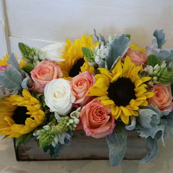 Sunflowers and peach roses arranged in a rectangular wooden box