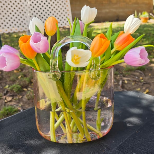 Colorful tulips arranged in a clear glass handbag vase