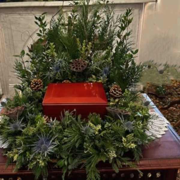 Green funeral wreath around a red urn on a table