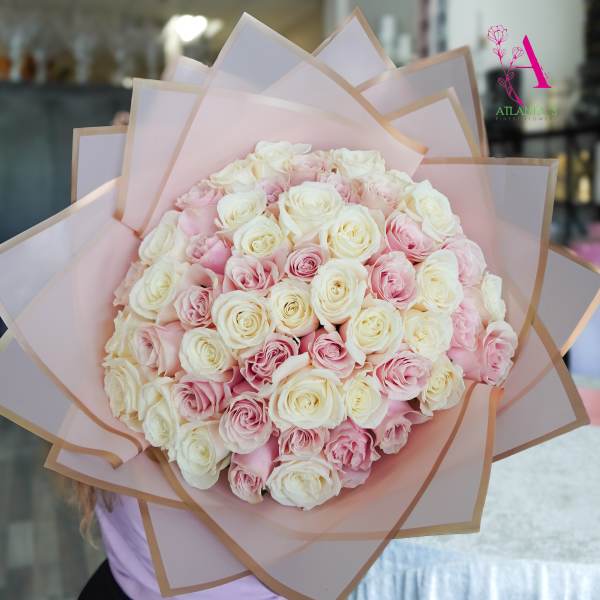 Large bouquet of pink and white roses wrapped in pale pink paper
