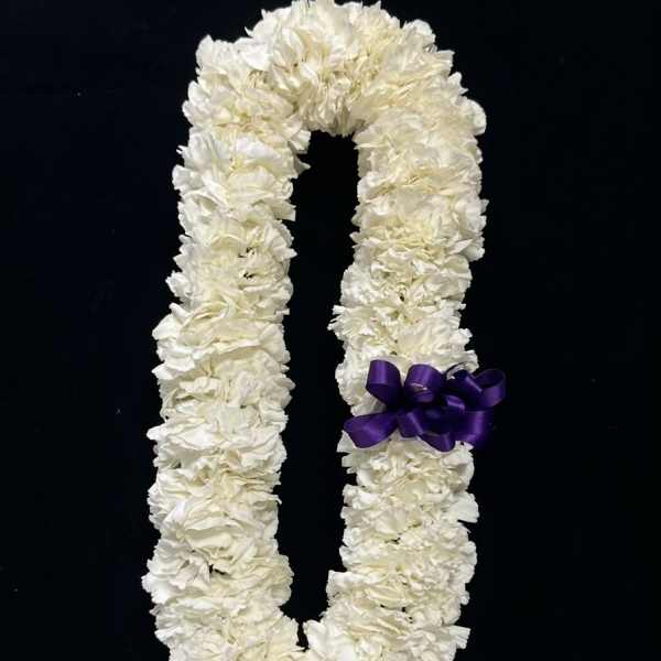 White floral lei with a purple ribbon on a black background
