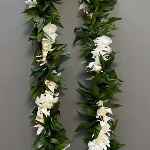 White flower lei with dense green leaves on a gray background