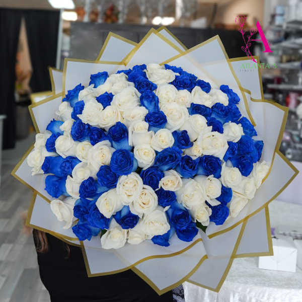 Large bouquet of blue and white roses wrapped in white paper with gold trim.