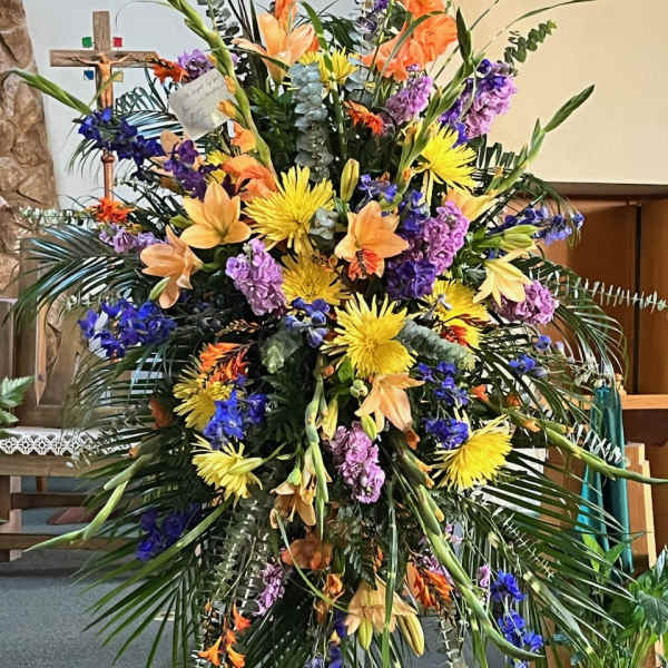 Large standing floral spray with yellow, orange, purple, and blue flowers