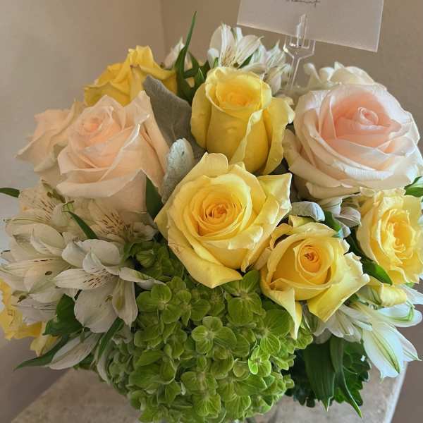 Bouquet of yellow and blush roses with white alstroemeria in a glass vase