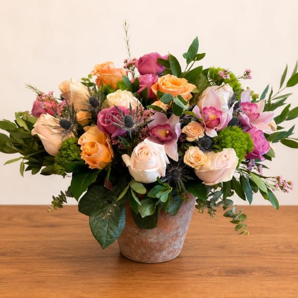 Mixed bouquet of roses and orchids in a terracotta pot