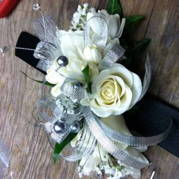 White rose corsage with silver ribbon and pearl accents on a black band