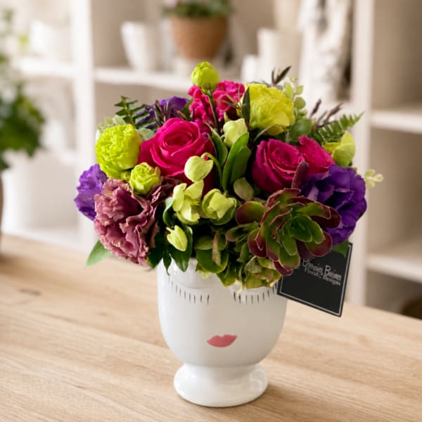 Colorful bouquet of roses, carnations, and hydrangeas in a white vase