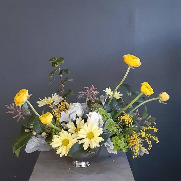 Yellow and white floral arrangement in a dark vase