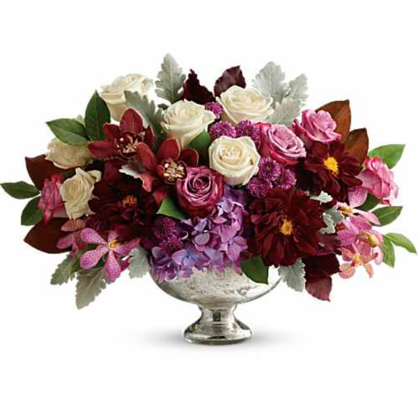 Mixed bouquet of roses, orchids, and hydrangeas in a silver pedestal vase