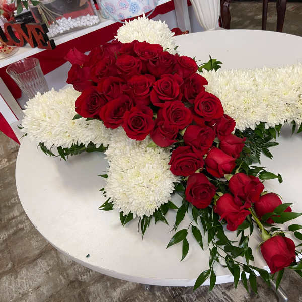 Red roses arranged over a white cross-shaped floral tribute