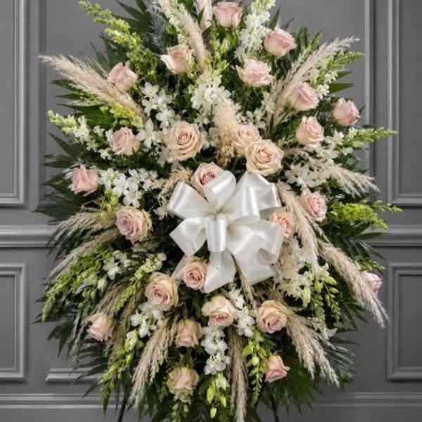 Standing floral spray with pale pink roses, white flowers, and a white bow
