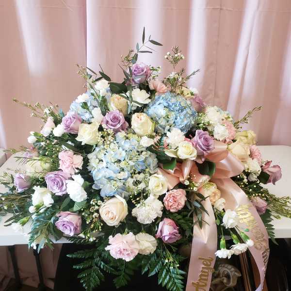 Large pastel floral arrangement with roses, hydrangeas, and carnations on a table