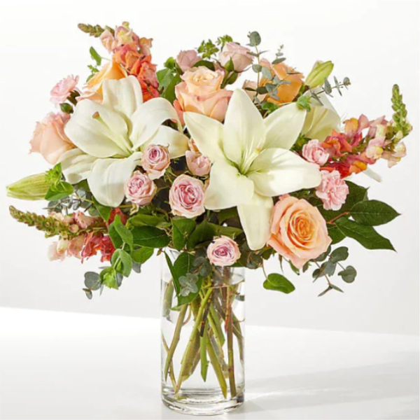 Bouquet of white lilies and peach roses in a clear glass vase
