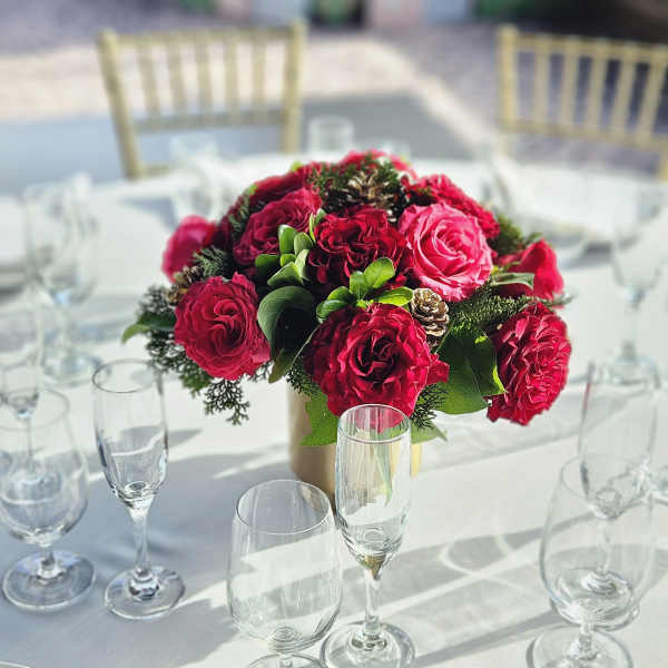 Red rose centerpiece in a gold vase on a set dining table