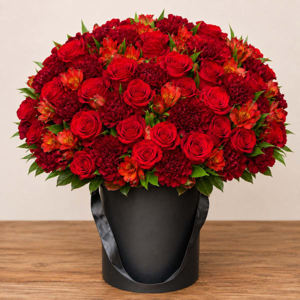 Red roses and orange flowers in a black hatbox