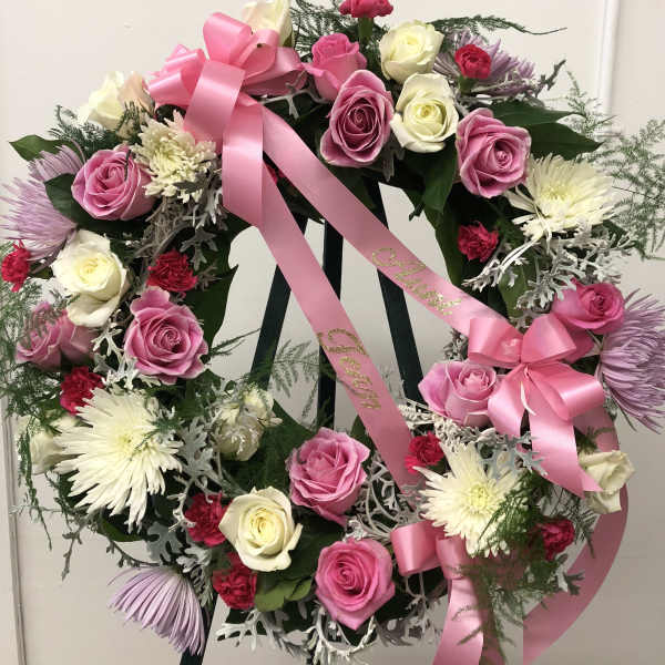 Pink and white rose wreath with ribbon on a stand