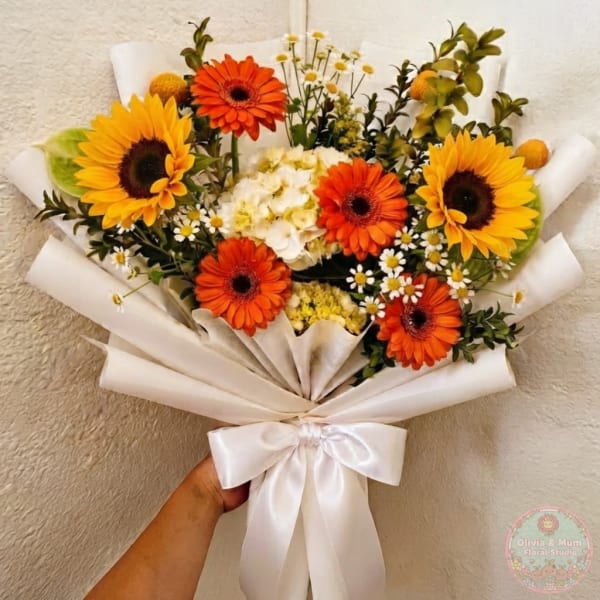 Bouquet of sunflowers and orange gerbera daisies wrapped in white paper