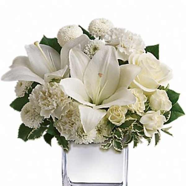 White floral arrangement in a clear square vase