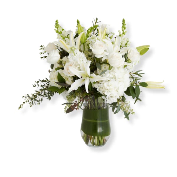 White floral arrangement in a glass vase with lilies and roses