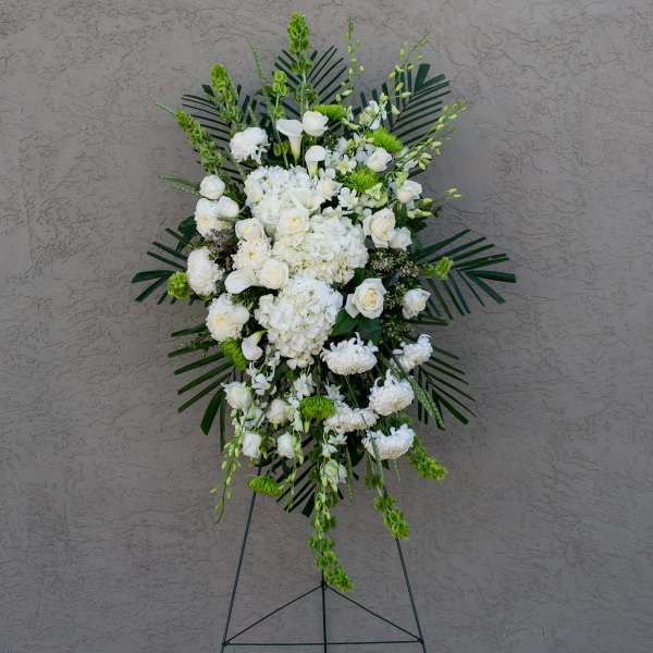 White floral standing spray on an easel with green accents