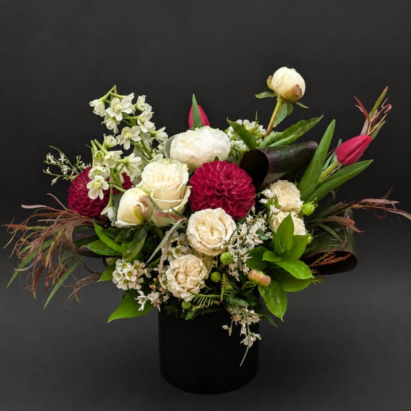Mixed bouquet of white and deep pink flowers in a black vase
