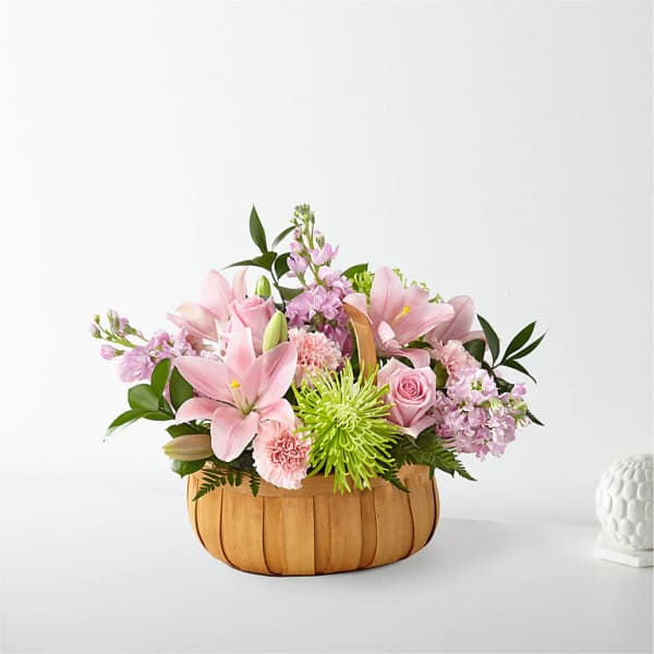 Pink lilies and mixed flowers arranged in a woven basket
