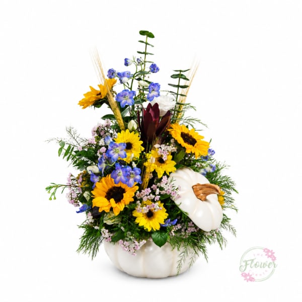 Sunflower and blue flower arrangement in a white pumpkin container