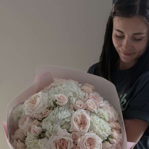 Large bouquet of pale pink roses and white hydrangeas wrapped in pink paper