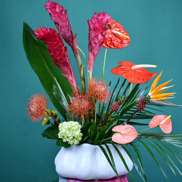 Tropical flower arrangement in a white vase with pink and orange blooms