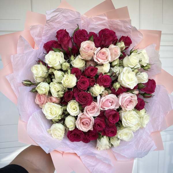 Bouquet of pink, white, and magenta roses wrapped in pastel paper
