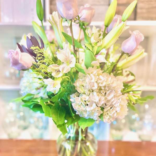 Pastel bouquet of roses, lilies, and hydrangeas in a glass vase