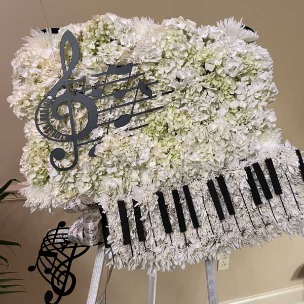 White floral standing spray with music note decorations on an easel