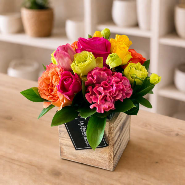 Bright mixed bouquet in a rustic wooden box with pink, yellow, and orange blooms
