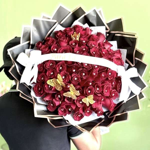 Large bouquet of deep red roses with black wrapping and white ribbon