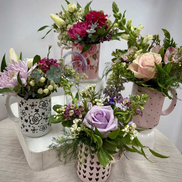Four floral mug arrangements with roses, lilies, and mixed blooms in pastel mugs.