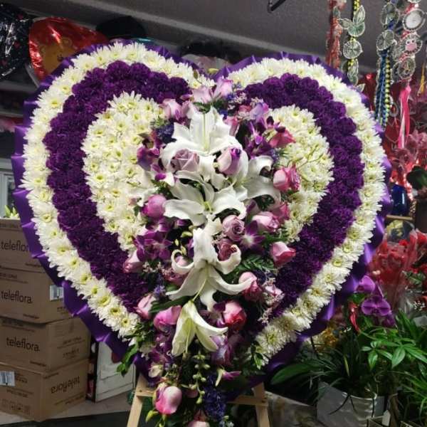 Heart-shaped floral standing spray with white, purple, and pink flowers