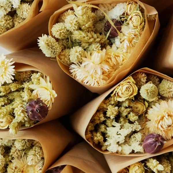 Bouquets of pale yellow and white dried flowers wrapped in brown paper