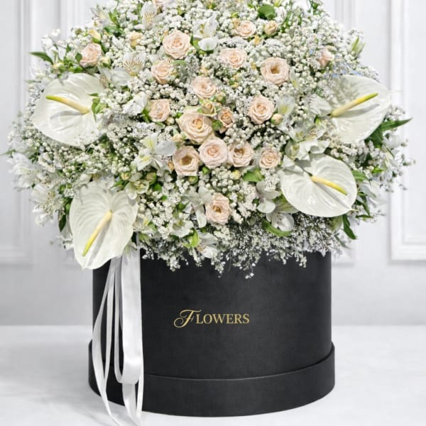 Large white floral arrangement with roses and calla lilies in a black hat box