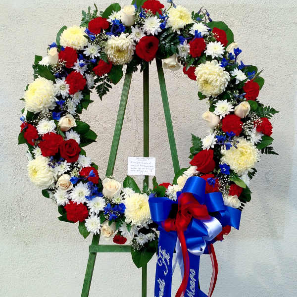 Large floral wreath with red, white, and blue flowers on a stand