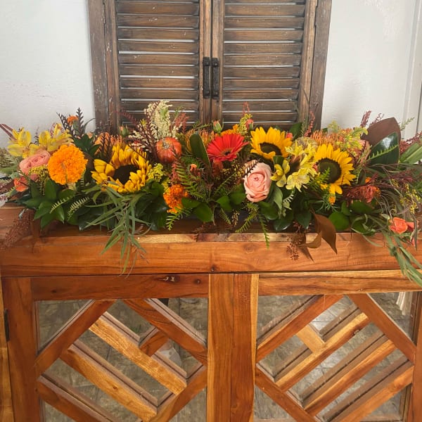 Long autumn floral arrangement with sunflowers, roses, and marigolds in a wooden container