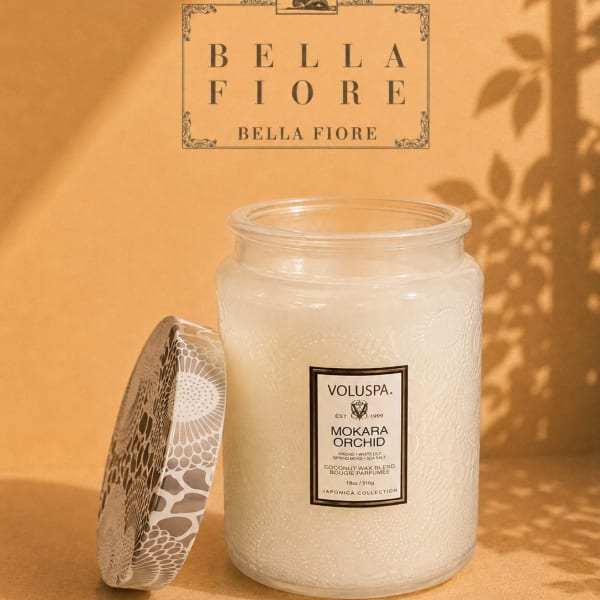 A white scented candle in a glass jar with a patterned lid