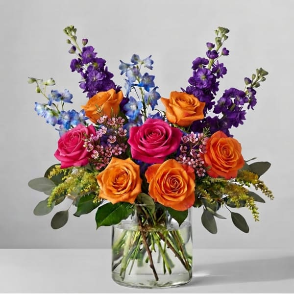 Bouquet of orange, pink, and purple flowers in a clear glass vase