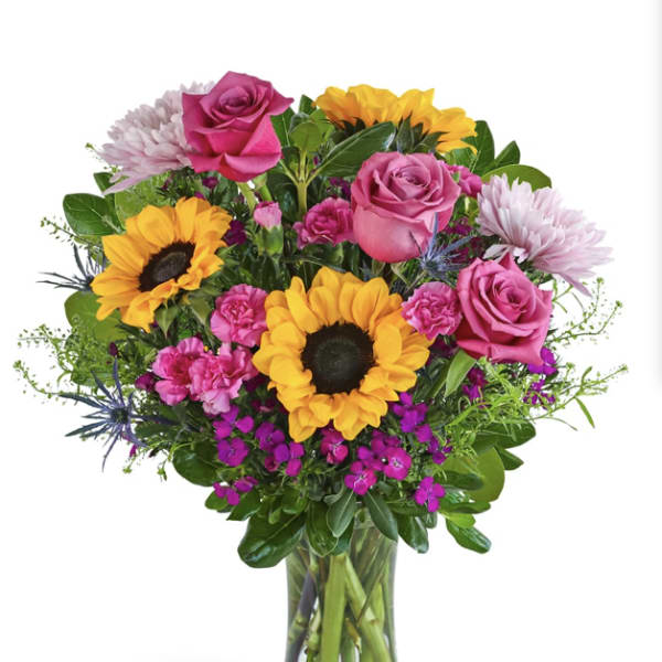 Bouquet of pink roses and sunflowers in a clear glass vase