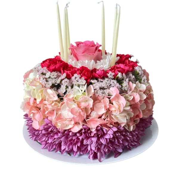 Round floral cake with pink and purple flowers and tall candles