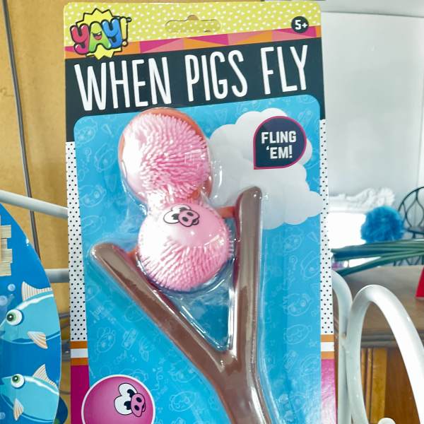 Packaged pig-themed toy slingshot with two pink pig balls