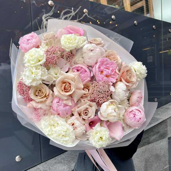 Large pastel bouquet of pink and cream flowers wrapped in translucent paper