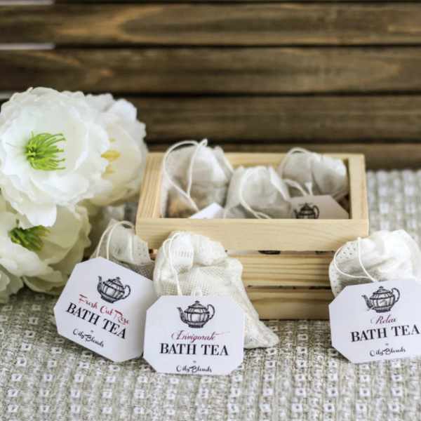 Bath tea sachets in a wooden box beside white flowers