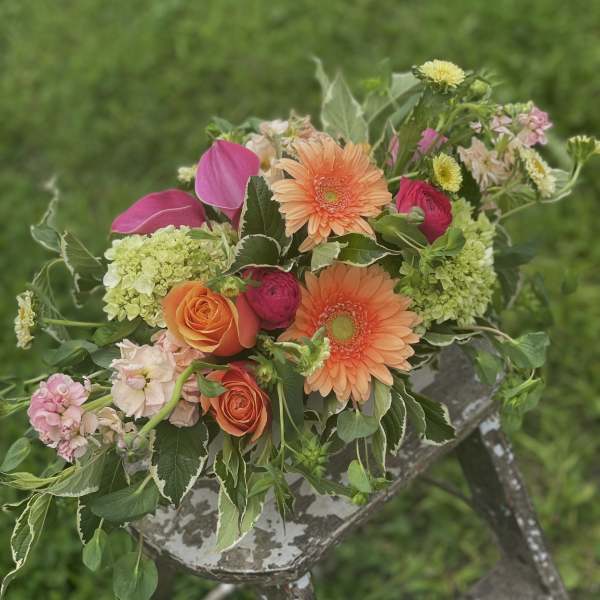 Mixed bouquet with orange gerbera daisies, roses, and pink blooms