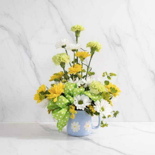 Yellow and white daisy bouquet in a blue mug with a green polka-dot bow